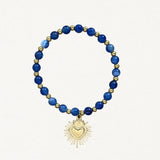 Bracelet fin perles Bleues avec pendentif cœur sacré doré sur fond blanc.