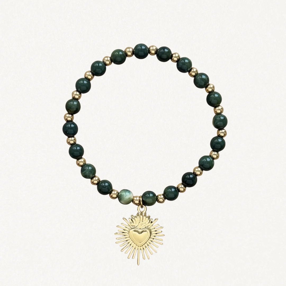 Bracelet fin perles Vertes avec pendentif cœur sacré doré sur fond blanc.