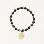 Bracelet fin perles Vertes avec pendentif cœur sacré doré sur fond blanc.