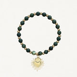 Bracelet fin perles Vertes avec pendentif cœur sacré doré sur fond blanc.
