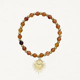 Bracelet fin perles Oranges avec pendentif cœur sacré doré sur fond blanc.