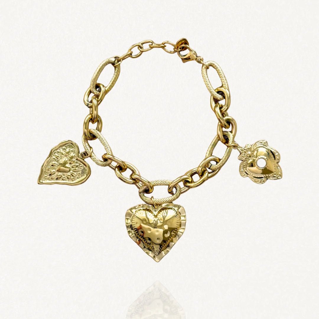 Vue d'ensemble bracelet chaîne maillons épais avec charms cœur et fleur dorés sur fond blanc.