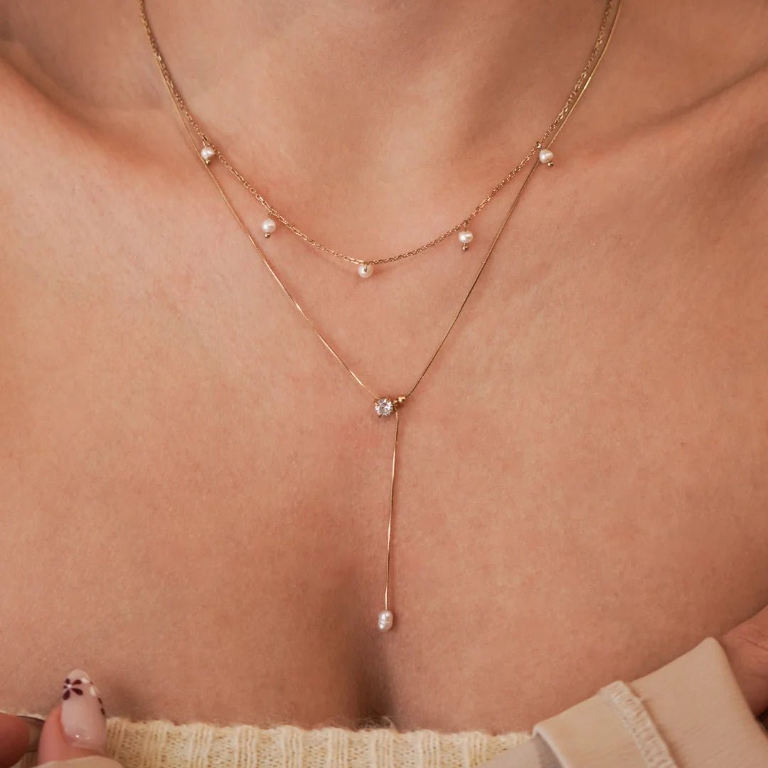 Collier Astrid porté en accumulation (stacking) avec un collier cravate plongeant pour un look bohème chic.