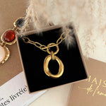 Collier doré à grosse chaîne et pendentif ovale organique, fermoir toggle, dans un écrin noir. Présence de pampas et autre bijou.