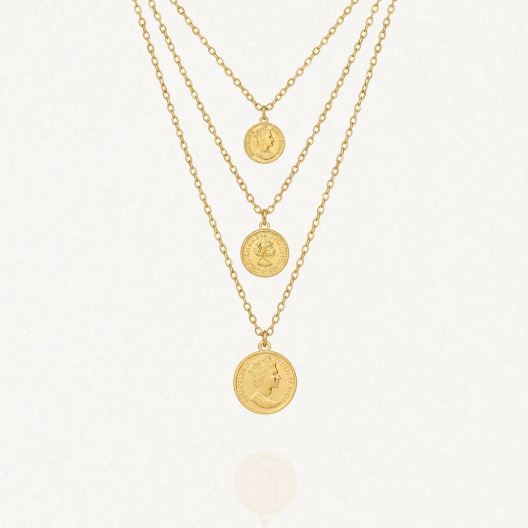 Collier multicouche doré avec trois chaînes de différentes longueurs. Chaque chaîne est ornée d'un pendentif médaille ronde gravée du profil de la Reine Elizabeth II.