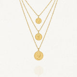 Collier multicouche doré avec trois chaînes de différentes longueurs. Chaque chaîne est ornée d'un pendentif médaille ronde gravée du profil de la Reine Elizabeth II.