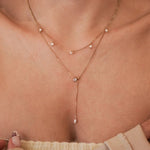 Collier Capucine porté en accumulation (layering) avec un collier ras-de-cou fin pour un look habillé.