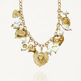 Collier doré MAISON DE L'AMOUR orné de breloques cœurs sacrés ex-voto et de perles blanches sur fond blanc.