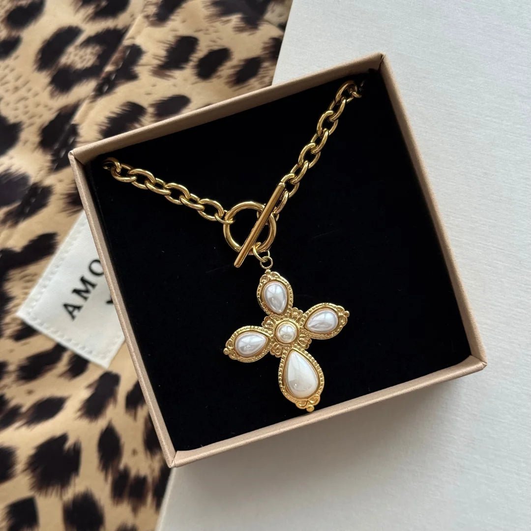 Collier pendentif croix style baroque Chloe présenté dans sa boîte cadeau sur une pochette léopard.