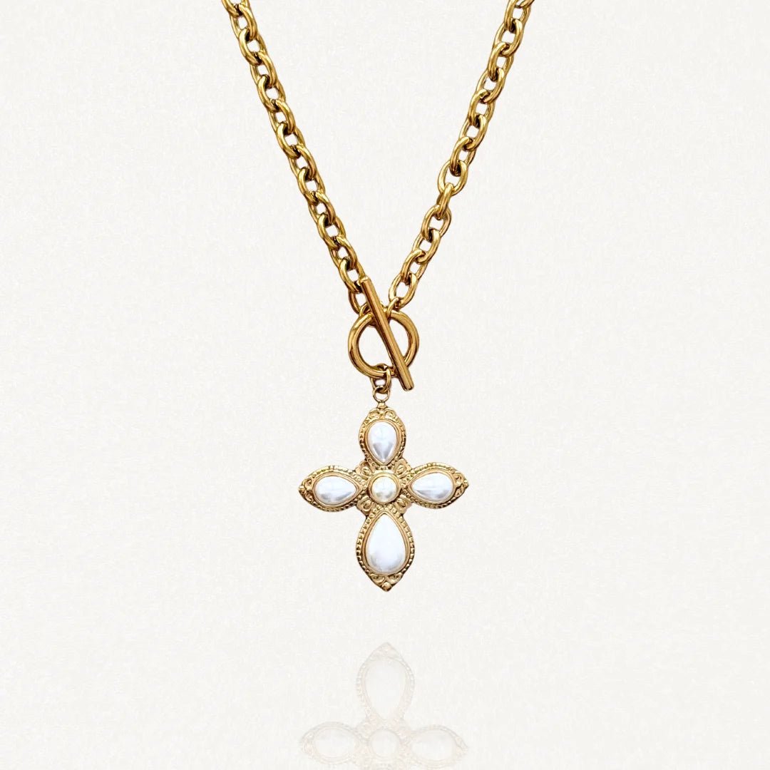 Vue d'ensemble collier chaîne épaisse dorée avec pendentif croix blanche et fermoir toggle sur fond blanc.