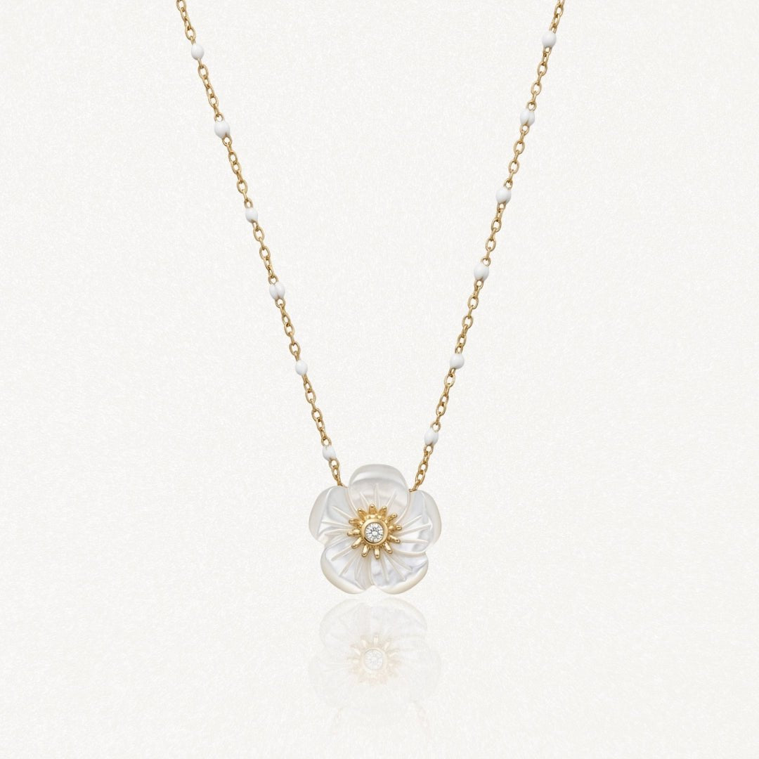 Collier en acier inoxydable: pendentif fleur en nacre irisée avec diamant central, chaîne dorée à billes blanches.