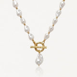 Collier en acier inoxydable doré avec perles baroques blanches, fermoir toggle et perle pendante.