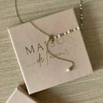 Collier fin style chapelet avec perles et chaîne pendante présenté sur sa boîte cadeau Maison de l'Amour.