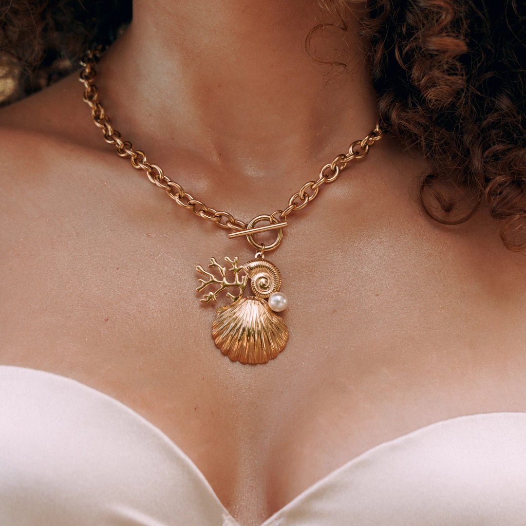 Collier en acier inoxydable doré, chaîne maillons épais avec fermoir toggle. Pendentif coquillages, perle et corail.