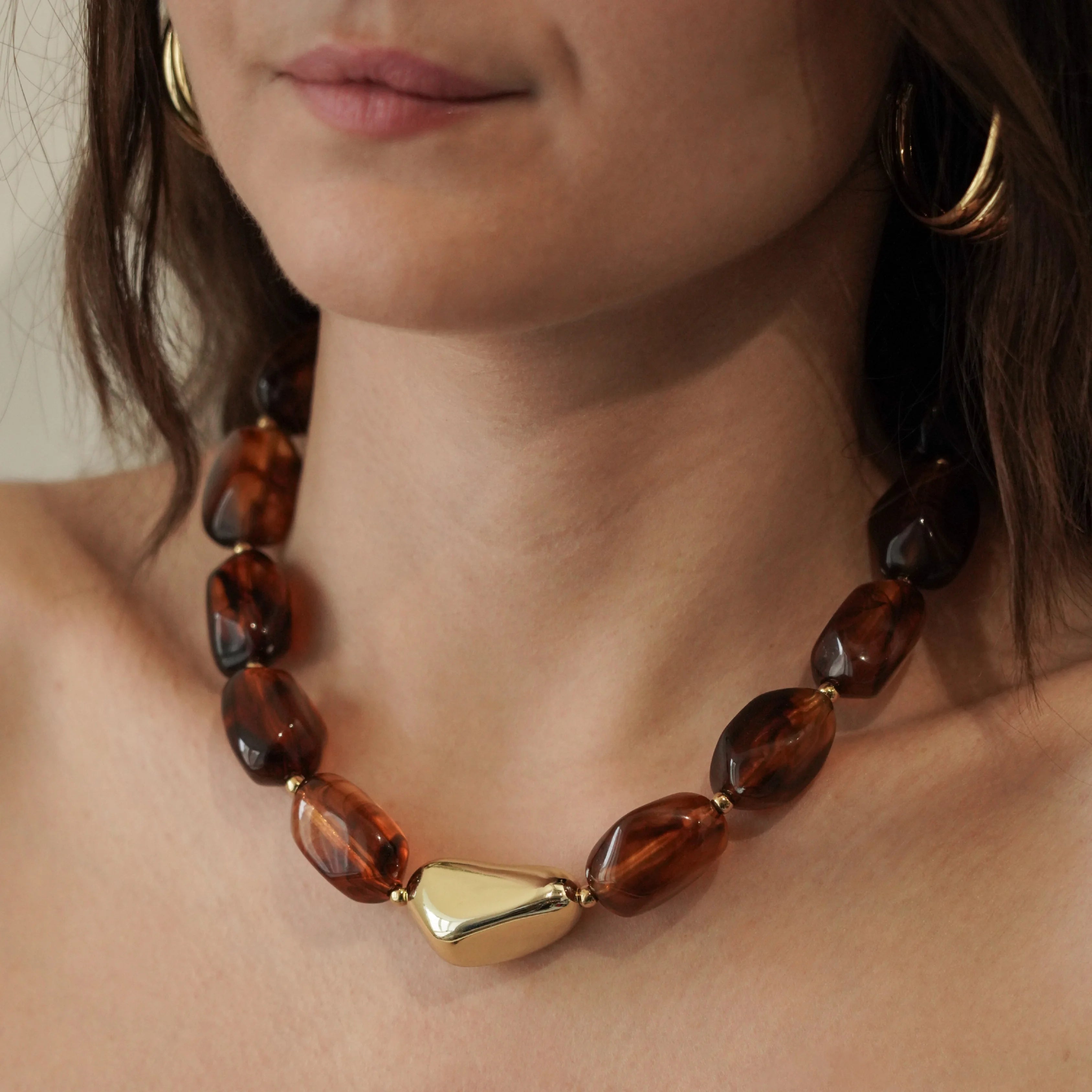 Collier court style choker en perles marron effet ambre avec détail doré central, bijou résistant à l'eau.