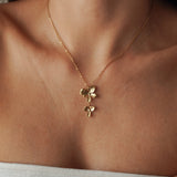 Collier fin en acier inoxydable doré avec pendentif double fleur en cascade porté au cou.