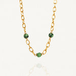 Collier grosse maille acier doré avec perles Vertes sur fond blanc.