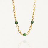 Collier grosse maille acier doré avec perles Vertes sur fond blanc.