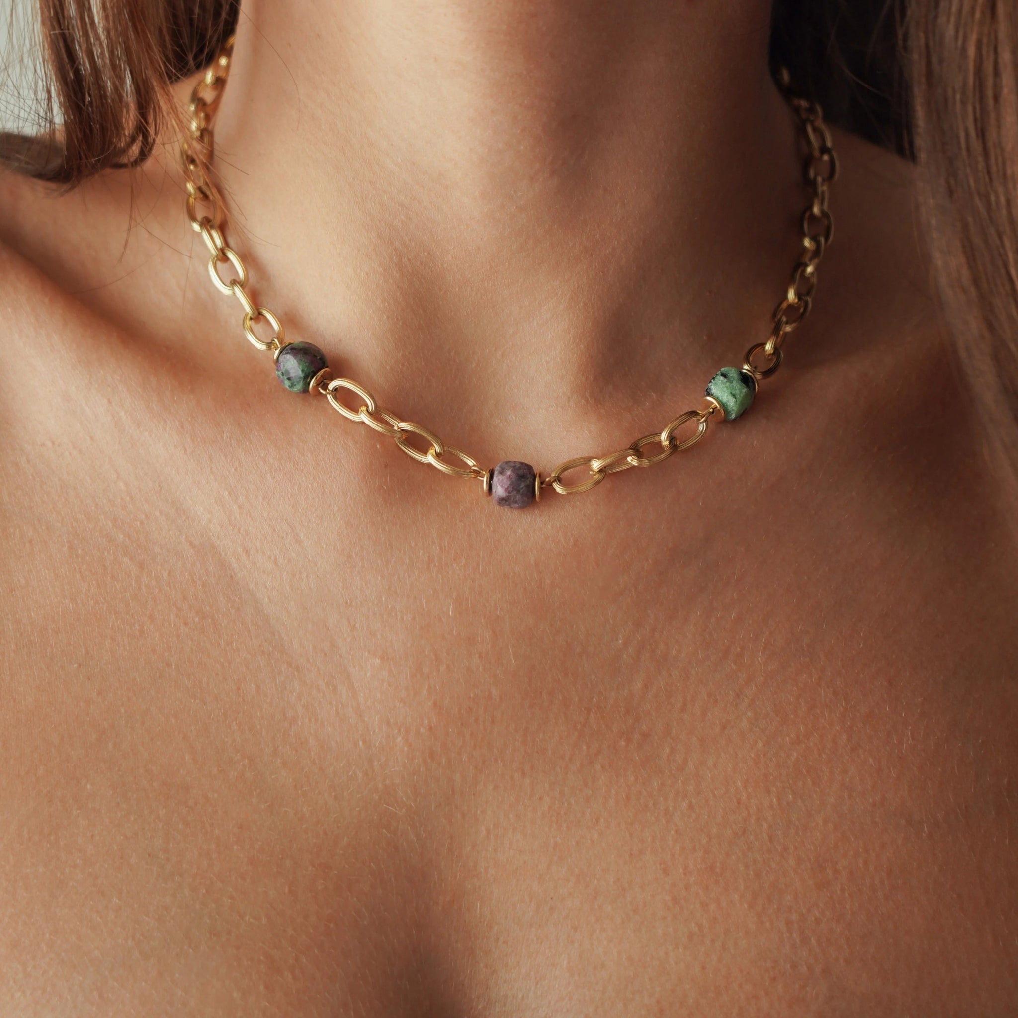 Collier ras-de-cou grosse maille en acier inoxydable doré alterné avec des perles cylindriques effet pierre naturelle porté au cou.