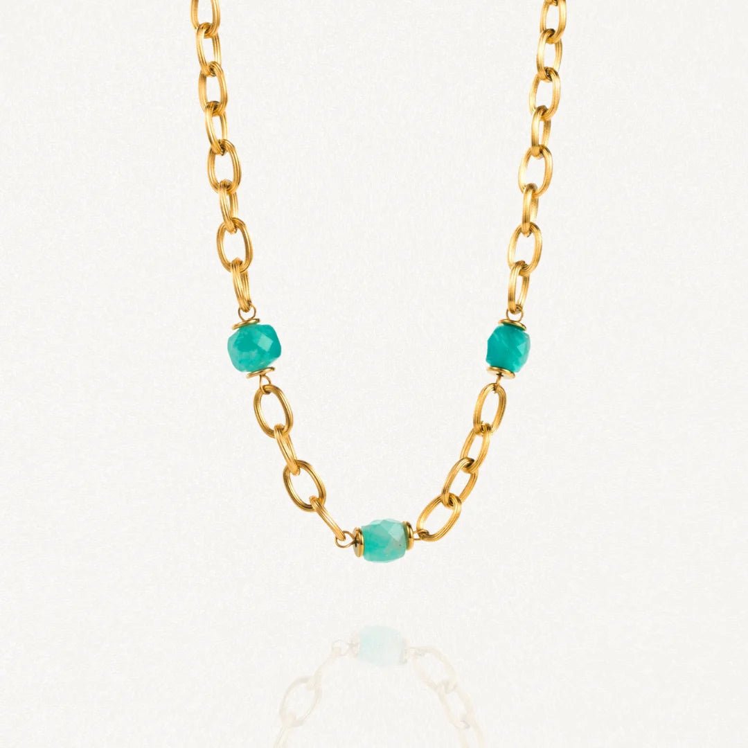 Collier grosse maille acier doré avec perles Turquoises sur fond blanc.