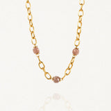 Collier grosse maille acier doré avec perles Roses sur fond blanc.