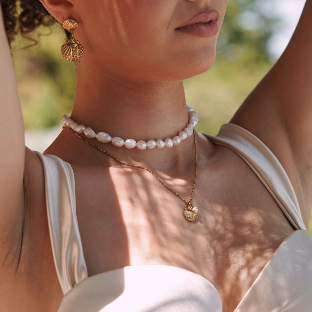 Collier chaîne fine doré en acier inoxydable avec pendentif coquillage texturé et 2 perles, porté.