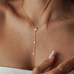 Collier cravate plongeant en acier inoxydable doré orné de petites étoiles du nord scintillantes porté au cou.