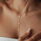 Collier cravate plongeant en acier inoxydable doré orné de petites étoiles du nord scintillantes porté au cou.