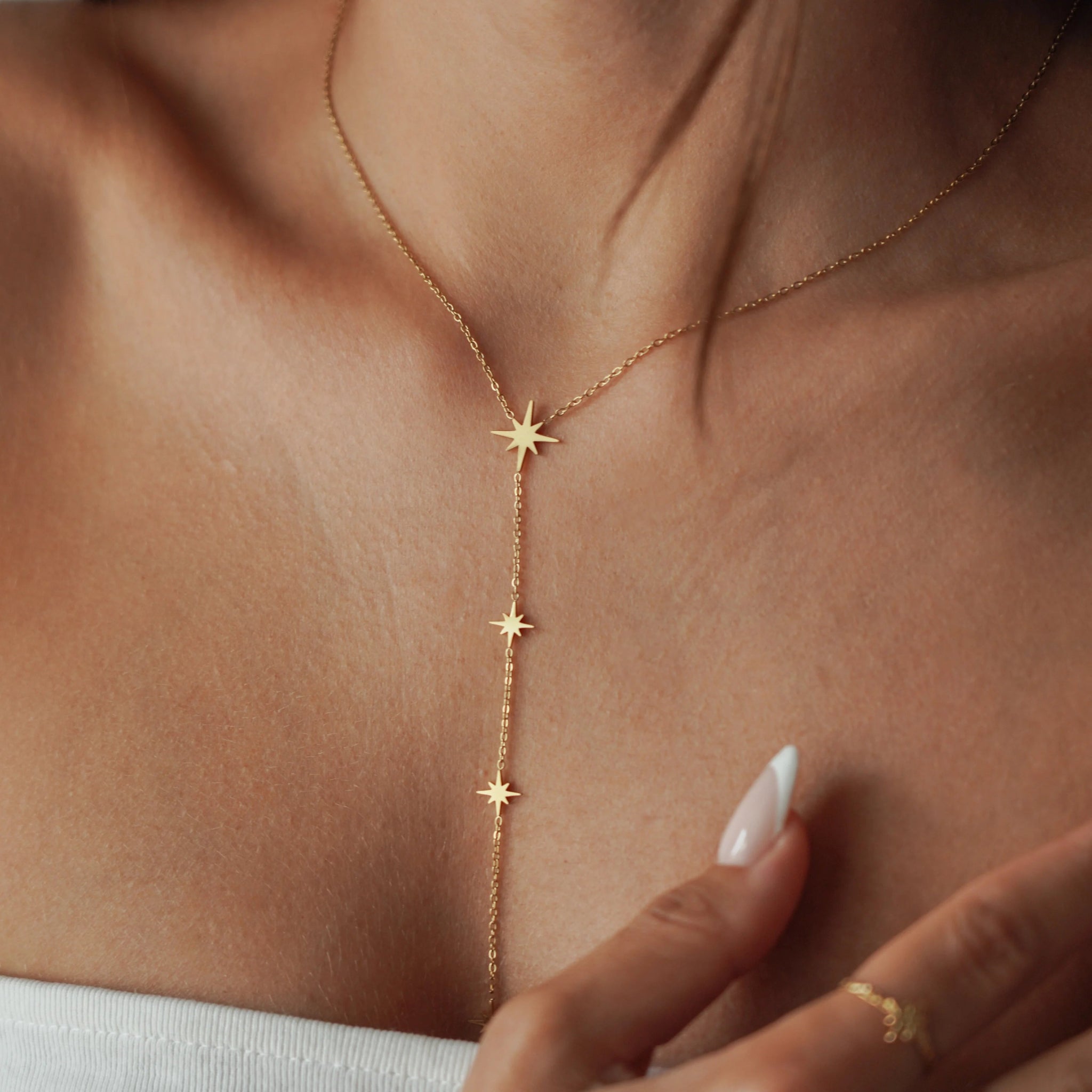 Collier cravate plongeant en acier inoxydable doré orné de petites étoiles du nord scintillantes porté au cou.