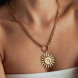 Collier grosse maille gourmette en acier inoxydable doré avec grand pendentif soleil visage porté au cou.