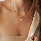 Collier double rang en acier inoxydable doré mariant une chaîne maille serpent plate et une chaîne fine avec pendentif perles blanches.