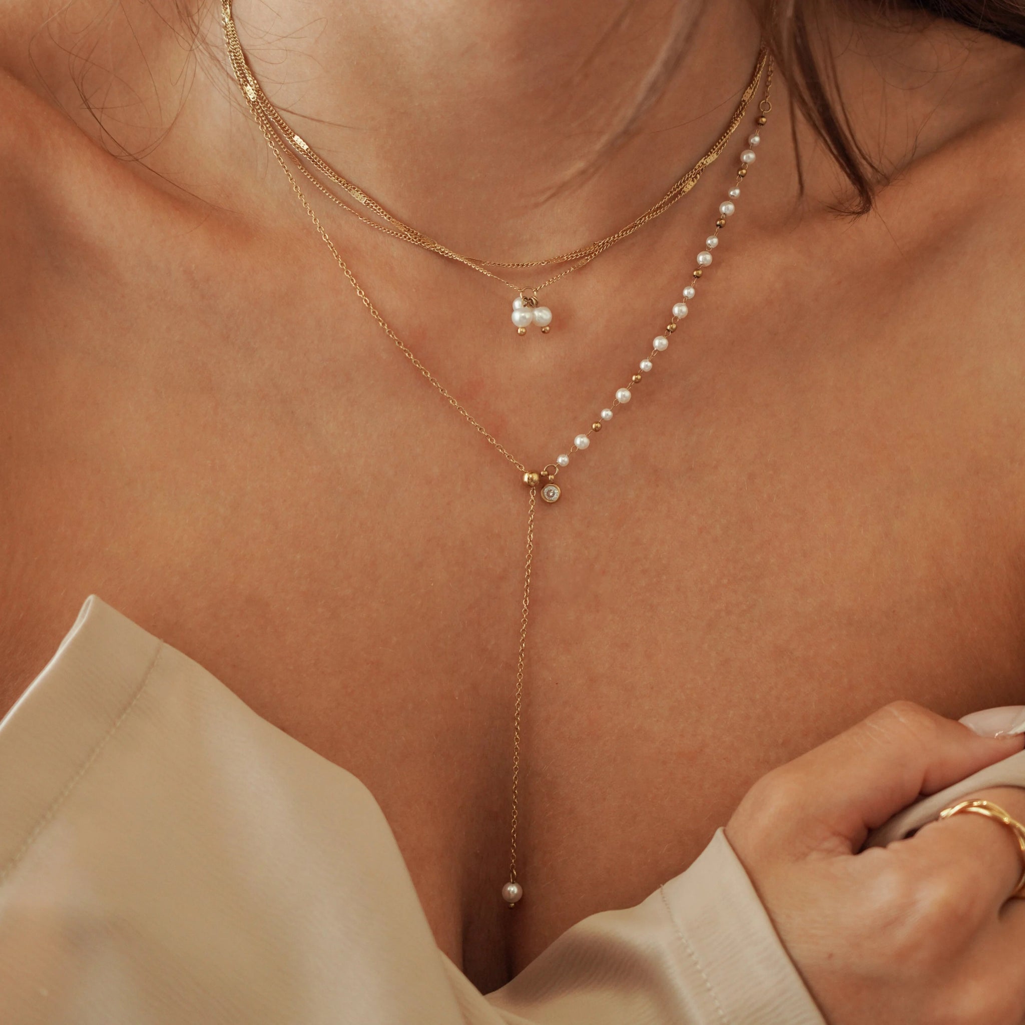 Collier double rang Manuela porté en accumulation (layering) avec un collier cravate plongeant.