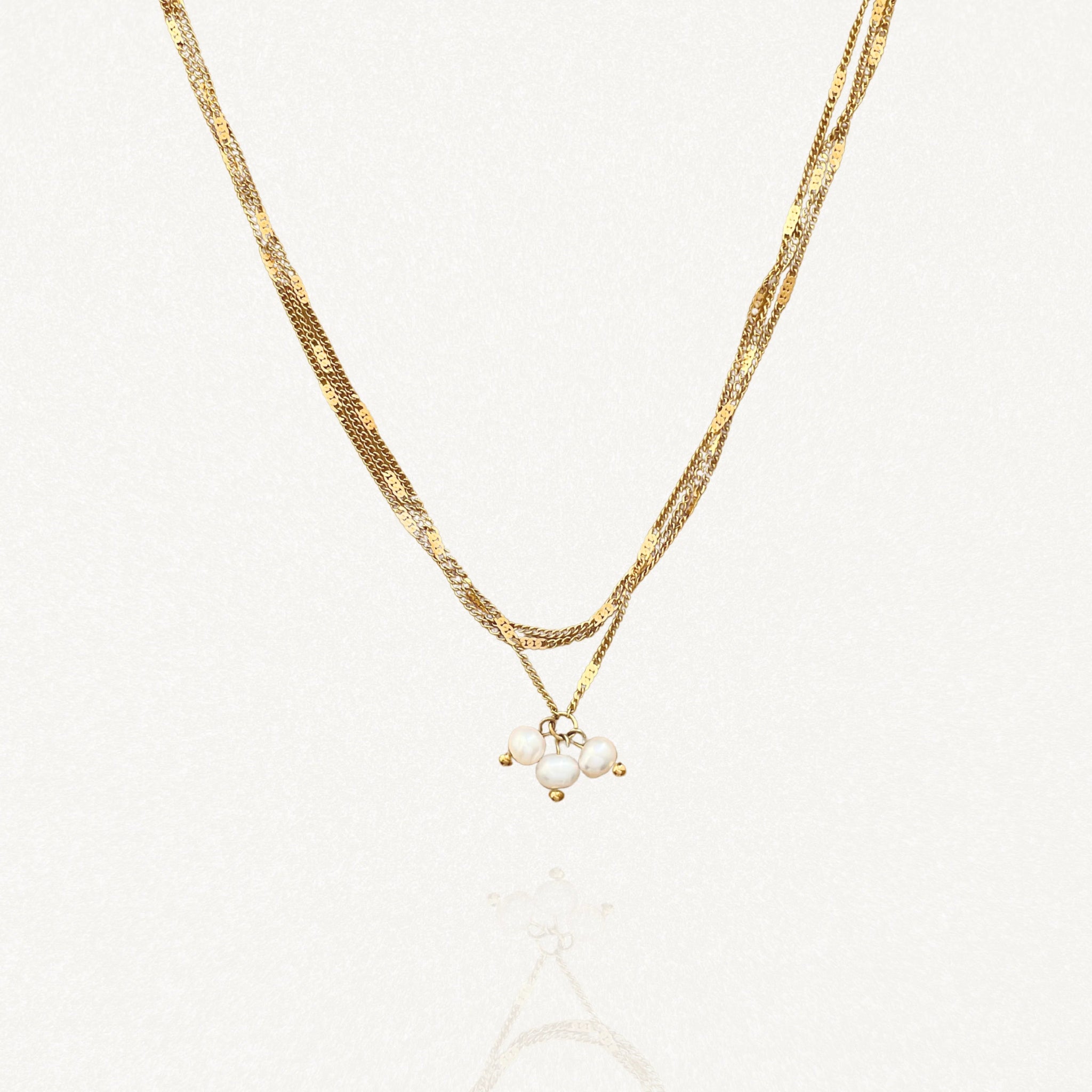 Vue d'ensemble collier effet double chaîne doré : maille serpent et petites perles sur fond blanc.