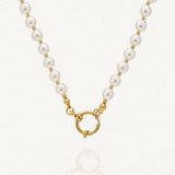Collier de perles blanches rondes et billes dorées avec fermoir anneau-ressort doré sur fond clair.