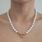 Collier de perles blanches nacrées rondes avec séparateurs dorés et fermoir anneau ressort doré, porté.