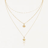 Collier 3 rangs en acier inoxydable doré, pendentifs étoile de mer et coquillage perlé.