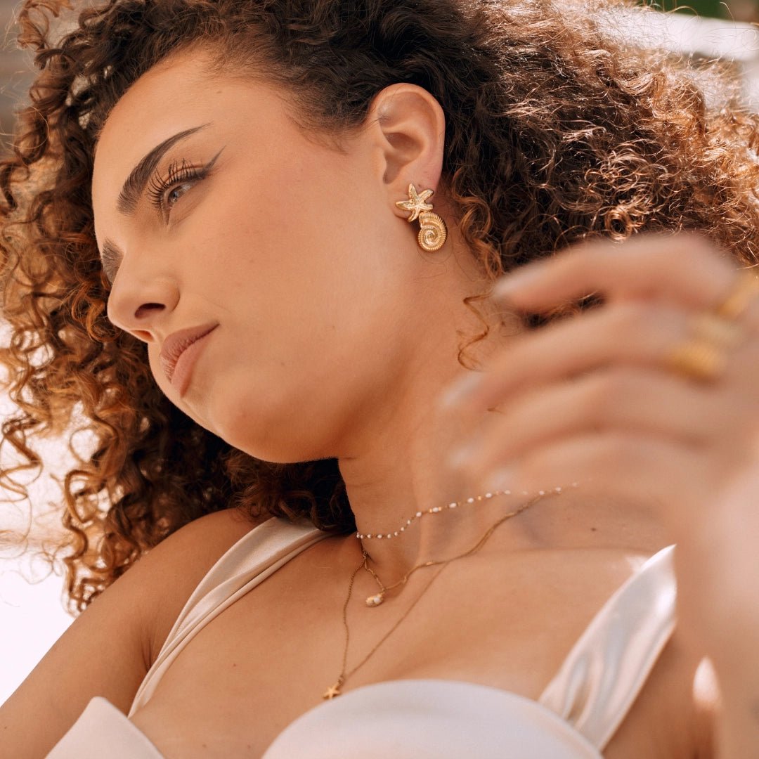 Collier en acier inoxydable double avec pendentifs perle et étoile, plus un collier ras de cou perlé sur femme.