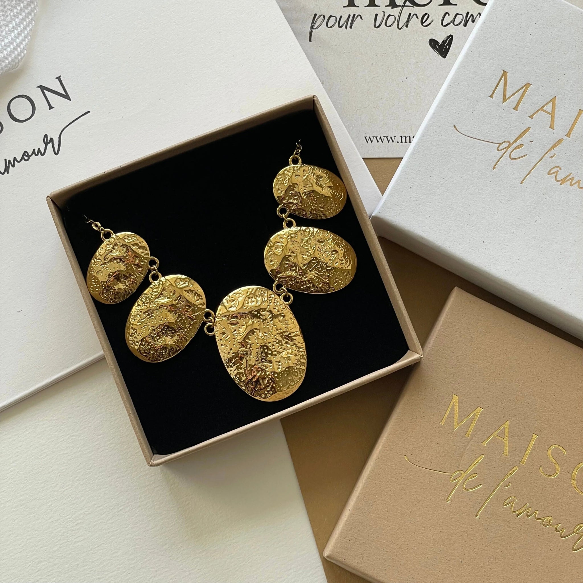 Collier à plastron médailles Rebecca présenté dans son coffret cadeau Maison de l'Amour.