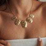 Collier style plastron léger en acier inoxydable doré composé de 5 médailles ovales texturées effet martelé ou pépite, porté au cou.