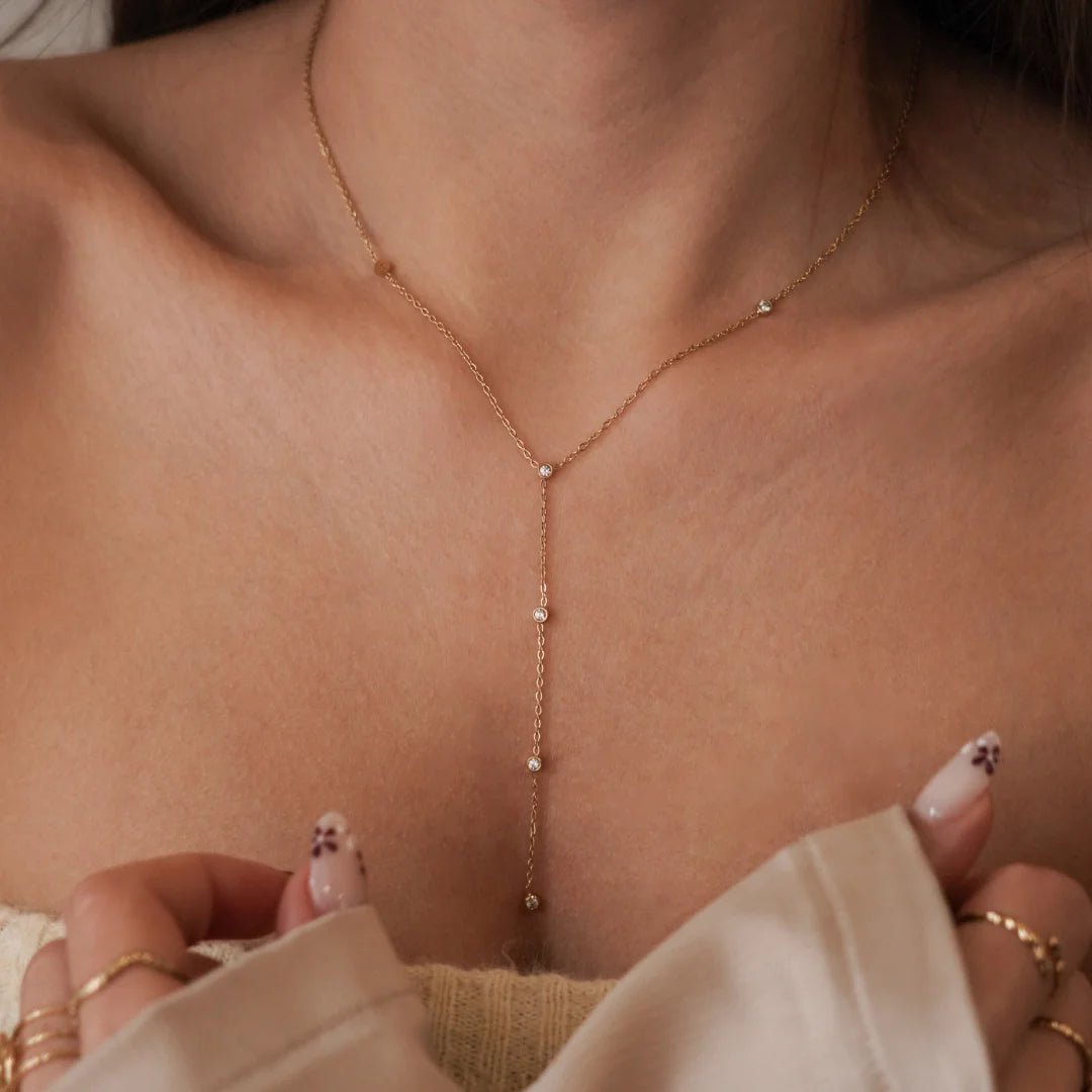 Collier cravate plongeant (forme Y) en acier inoxydable doré orné de petits cristaux ou strass scintillants sur la chaîne pendante.