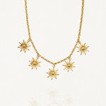 Vue d'ensemble collier chaîne dorée avec multiples pendentifs motifs solaires rayonnants sur fond blanc.