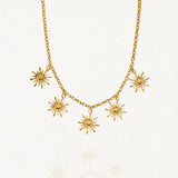 Vue d'ensemble collier chaîne dorée avec multiples pendentifs motifs solaires rayonnants sur fond blanc.