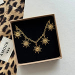 Collier à pampilles soleils Zoe présenté dans son coffret cadeau Maison de l'Amour sur fond léopard.