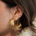 Gros plan sur l'oreille : boucle d'oreille créole large triple rangs, bijou statement pour femme.