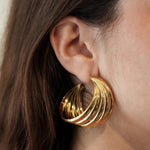 Créole dorée style vintage portée, design texturé effet multiples anneaux en acier résistant.