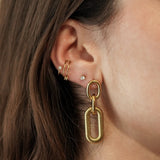 Femme portant les boucles d'oreilles à maillons dorés, accessoire chic et géométrique idéal pour un look moderne.