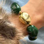 Zoom sur un bracelet porté au poignet, montrant le détail des perles vertes marbrées et de la grosse perle centrale dorée asymétrique.