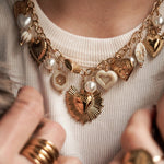 Détail mode : accumulation collier et bracelet cœurs dorés portés avec un manteau en fausse fourrure.