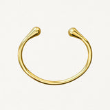 Vue de dessus d'un bracelet jonc ouvert doré montrant sa forme ovale ergonomique et ses finitions lisses.