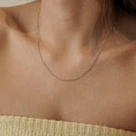 Collier fin argenté porté sur le cou, détail discret et élégant pour une tenue de tous les jours.